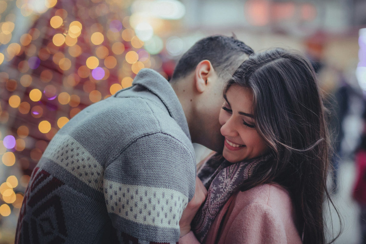 A couple embracing in front of Christmas lights