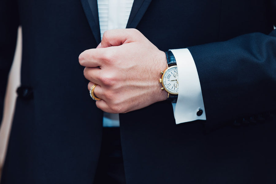 Man in a suit fastening his cuff, watch on his wrist