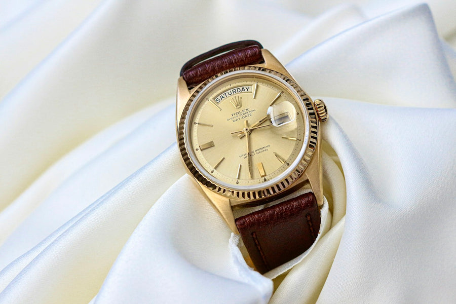 A vintage gold watch resting on a white cloth