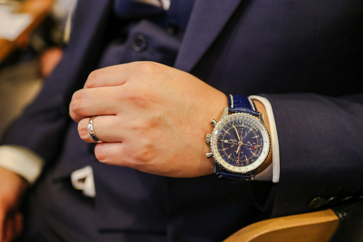 A man in a navy suit, his automatic watch on his wrist